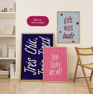 three framed pieces of art on a wall, including a large blue frame with white text, a pink frame with white text, and a blue and white striped frame with red stars.